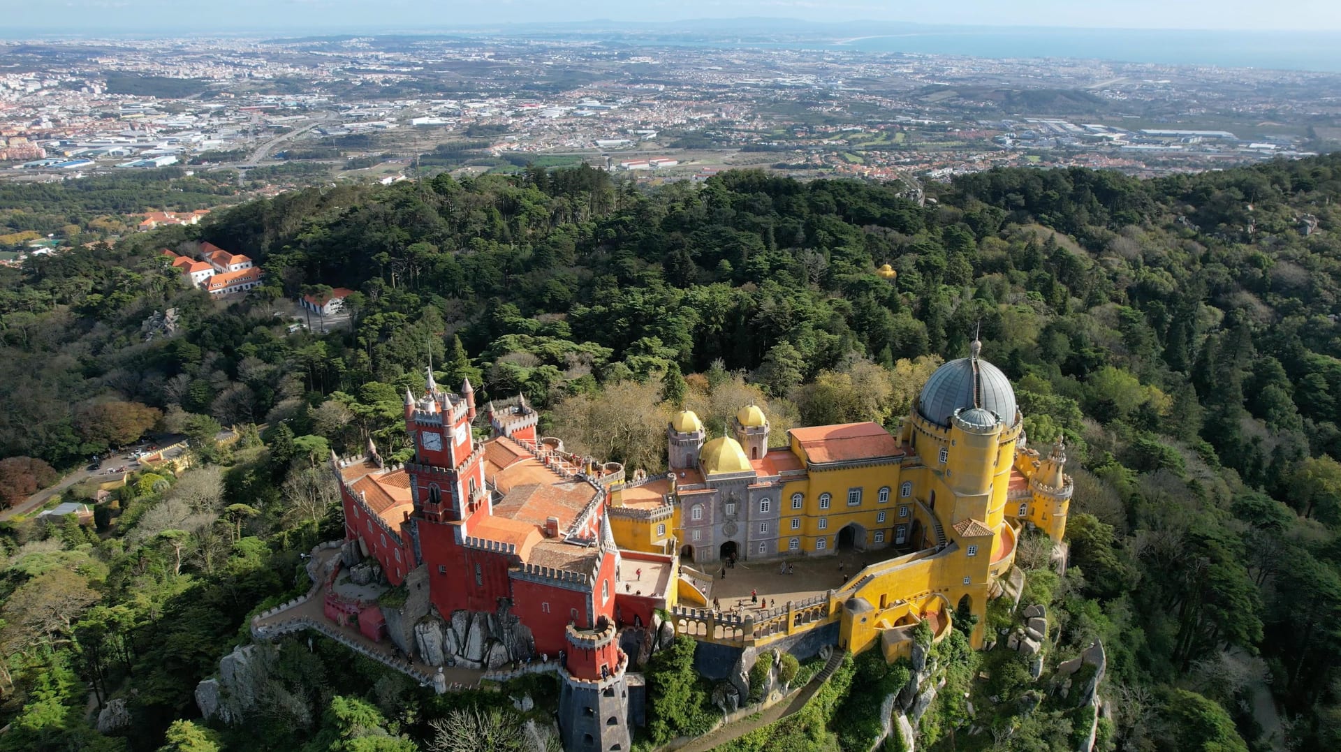 Pena Palace seen from below, the iconic red and yellow towers rising above the Serra de Sintra forest.